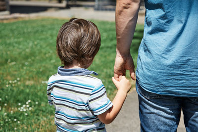 Dad takes a little boy, son by the hand to kindergarten or school on a sunny day. care of parents