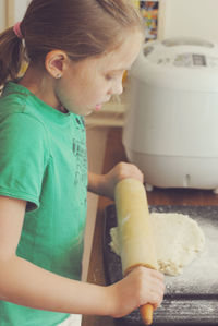 Girl rolling dough for pizza at table
