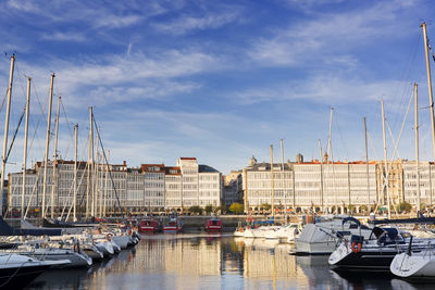 Boats moored at harbor against sky