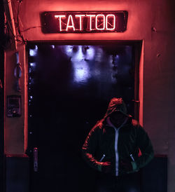 Man standing at entrance with neon sign