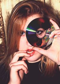Portrait of young woman looking through compact disc