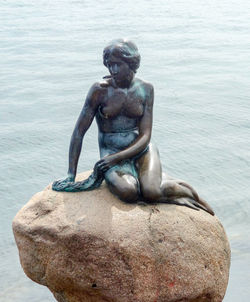 Statue on rock by sea