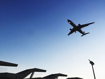 Low angle view of airplane against clear blue sky