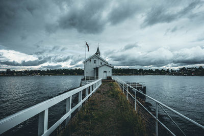 Traditional windmill by lake against sky