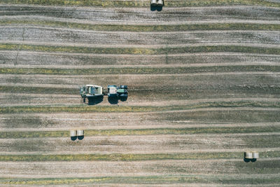 An agricultural tractor collects mowed grass for agricultural use and wraps hay bales 