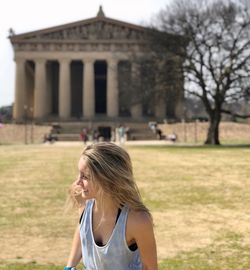 Woman wearing hat standing against built structure