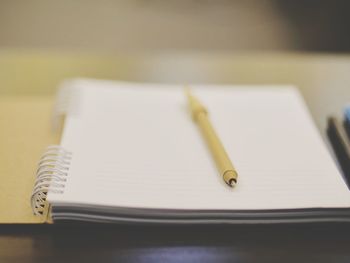 Close-up of pen and spiral notebook on table