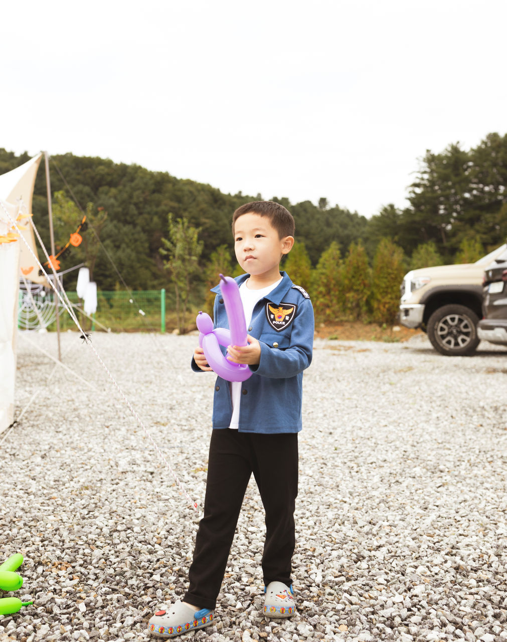 one person, car, full length, child, transportation, childhood, standing, nature, motor vehicle, land vehicle, spring, lifestyles, front view, vehicle, mode of transportation, day, clothing, person, leisure activity, portrait, emotion, adult, women, footwear, men, smiling, sky, holding, outdoors, looking at camera, plant, happiness, casual clothing, road, female