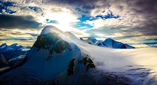 Scenic view of snowcapped mountains against cloudy sky