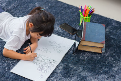 High angle view of woman drawing on paper