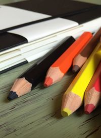 Close-up of colored pencils by book on table