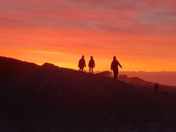 Silhouette people walking on mountain road against sky during sunset