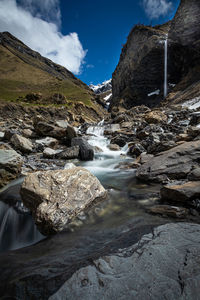 River flowing through rocks against sky