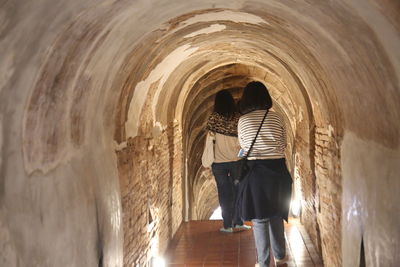 Rear view of woman standing in tunnel