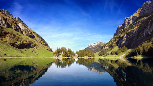 Scenic view of lake and mountains against blue sky