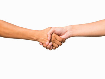 Midsection of couple holding hands against white background