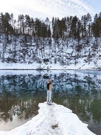 Woman standing by lake during winter
