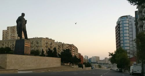 Statue in city against clear sky