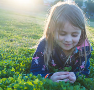 Smiling girl holding leaves while lying on plants