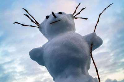 Low angle view of snowman against sky