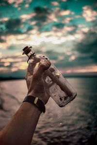 Close-up of hand holding statue against sky