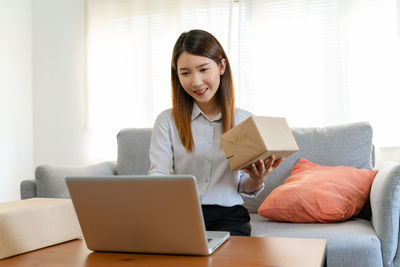 Young woman using laptop while sitting on sofa at home