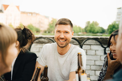 Portrait of happy man sitting with friends and enjoying at social gathering