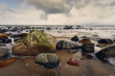 Rocks on beach against sky during sunset