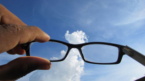 Close-up of cropped hand against blue sky