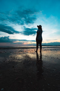 Silhouette woman standing beach against sky during sunset