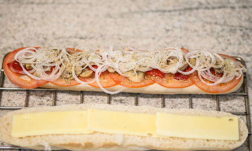 High angle view of vegetable slices and cheese on baguette at table