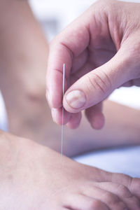 Close-up of doctor inserting needle in patient foot at hospital