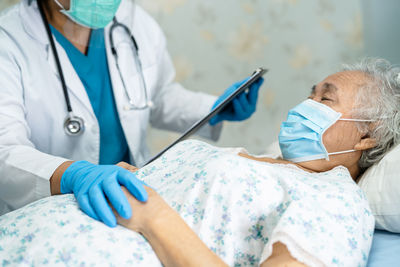 Midsection of doctor examining senior woman in hospital