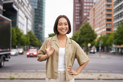 Portrait of young woman standing in city