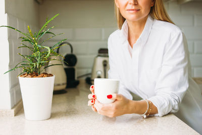 Midsection of woman holding coffee mug on table