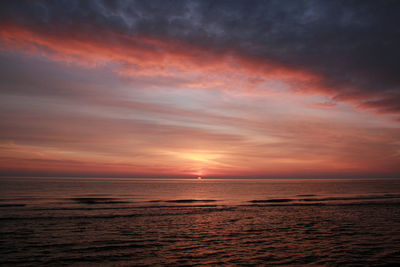 Scenic view of sea against dramatic sky during sunset