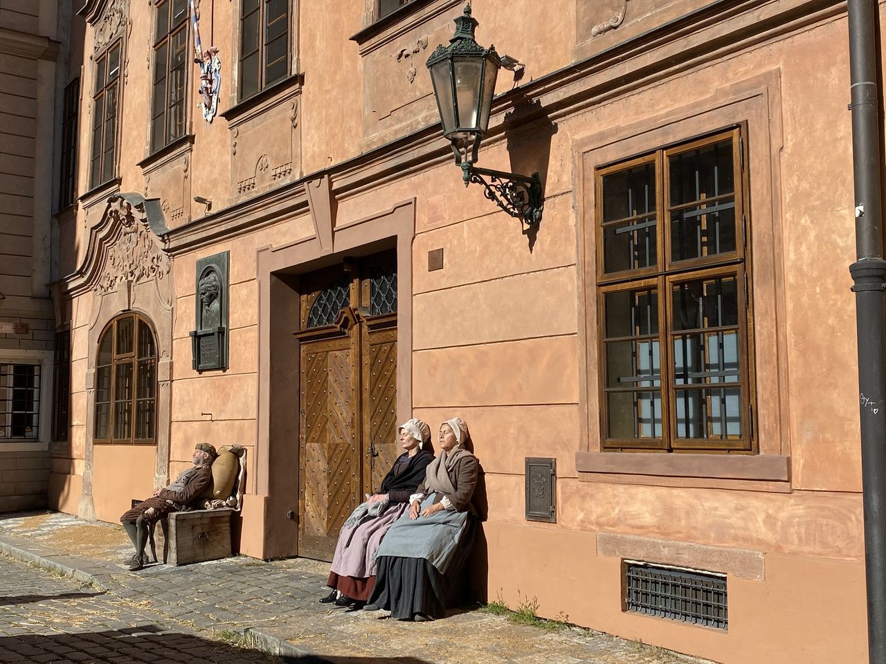 PEOPLE SITTING ON STREET AGAINST BUILDING