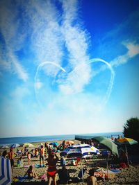 People at beach against blue sky