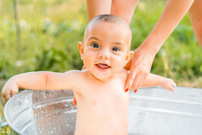 Portrait of shirtless boy sitting in bathtub outdoors