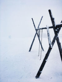 Crane on snow covered field against sky