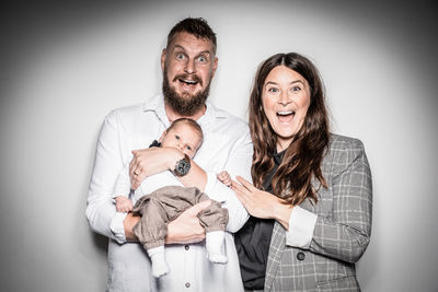 Portrait of shocked family standing against white background