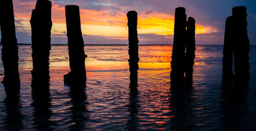 Silhouette pier on sea during sunset