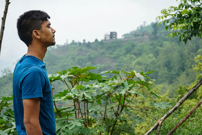 Side view of young man looking at plants