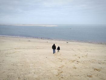 Rear view of father and son walking on beach