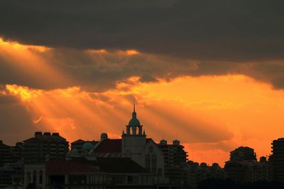 Buildings against cloudy sky at sunset