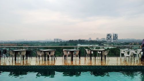 Buildings by river against sky in city