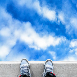 Low section of woman standing against blue sky