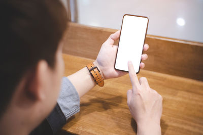 Midsection of man using mobile phone on table