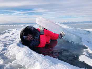 Portrait of happy woman lying on frozen lake