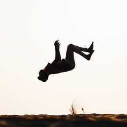 Low angle view of man jumping against sky during sunset